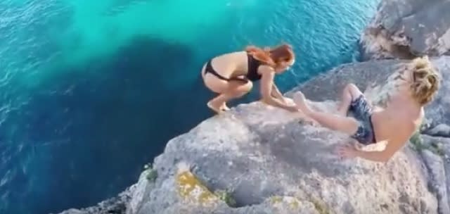 Girl grabs for boyfriend's leg in failed cliff dive, he pulls away