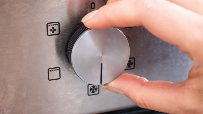Hand turning dial on oven