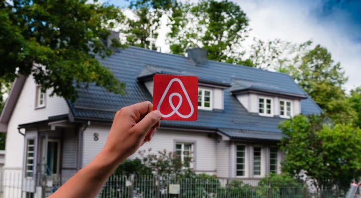 A hand holds up the Airbnb (ABNB) logo outside a home in Estonia.