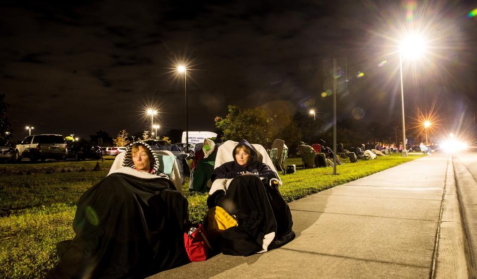 Terri Kado, 66, right, and Patty Tubbs, 68, friends from Fort Myers Beach, Florida, wait in line for a COVID-19 vaccine in the early morning hours of Dec. 30 at Lakes Park Regional Library.