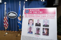 A poster showing six wanted Russian military intelligence officers is displayed before a news conference at the Department of Justice, Monday, Oct. 19, 2020, in Washington. (AP Photo/Andrew Harnik, pool)
