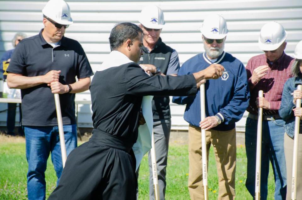 Father Lourdu Mummadi blesses the land with holy water that will soon house six more classrooms at Tri-Cities Prep Catholic High School at 9612 St. Thomas Drive in Pasco, Washington.