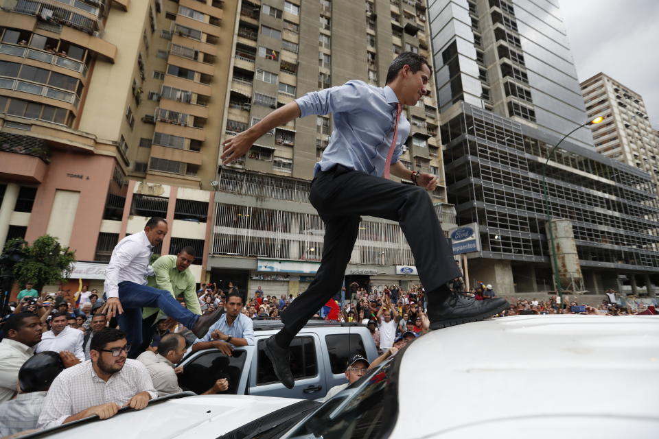National Assembly President Juan Guaido, who declared himself interim president of Venezuela, leaps on to a vehicle to speak to supporters as he visits different points of anti-government protest in Caracas, Venezuela, Tuesday, March 12, 2019. Guaido has declared himself interim president and demands new elections, arguing that President Nicolas Maduro's re-election last year was invalid. (AP Photo/Eduardo Verdugo)
