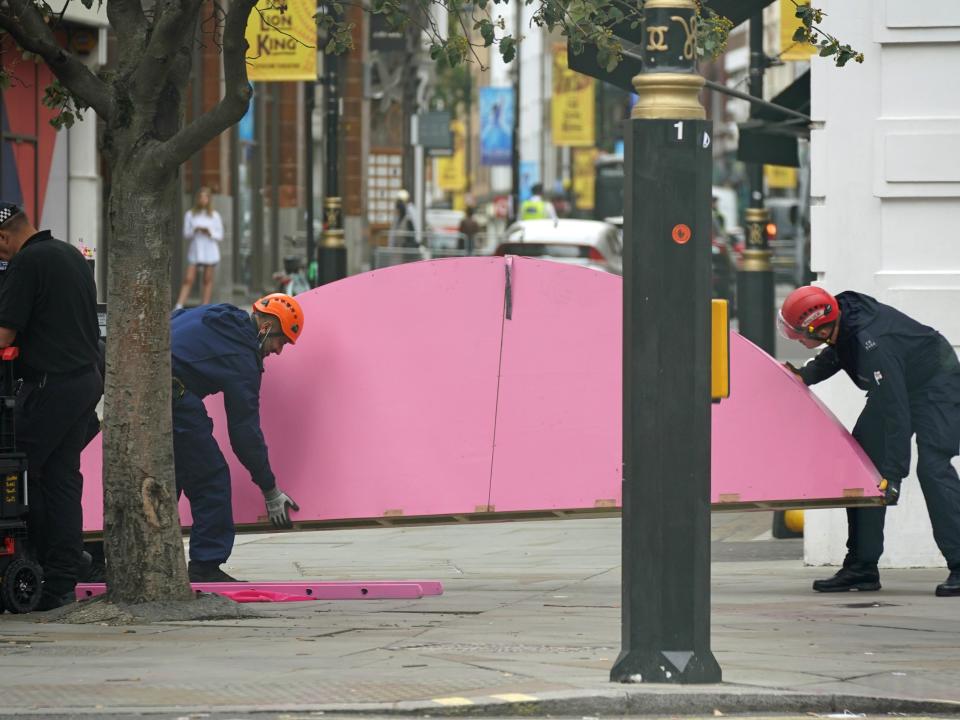 Part of the table’s top, on which XR protesters sat yesterday, is carried off by workers, watched over by police (PA)