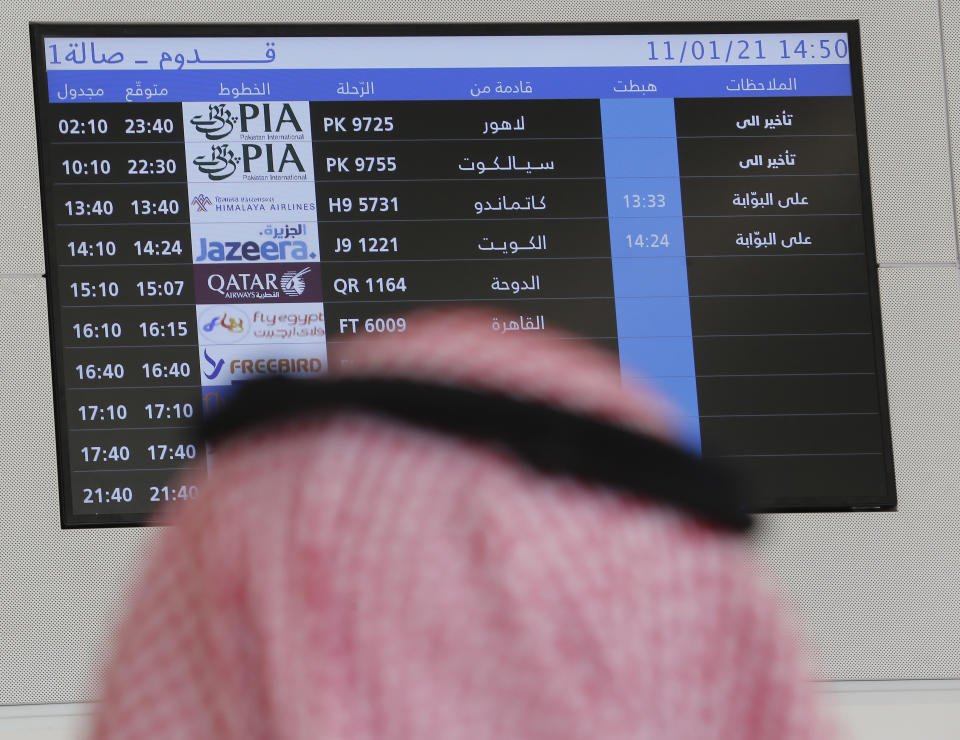 A Saudi waits for the arrival of relatives from Qatar in front of a screen displaying a Qatar Airways flight for the first time in 3 years, at King Khalid Airport in Ryadh, Saudi Arabia, Monday, Jan. 11, 2021. Saudi Arabia, along with the UAE, Bahrain and Egypt, ended a three-year dispute with Qatar following a Gulf Cooperation Council (GCC) summit in AlUla last week. (AP Photo/Amr Nabil)