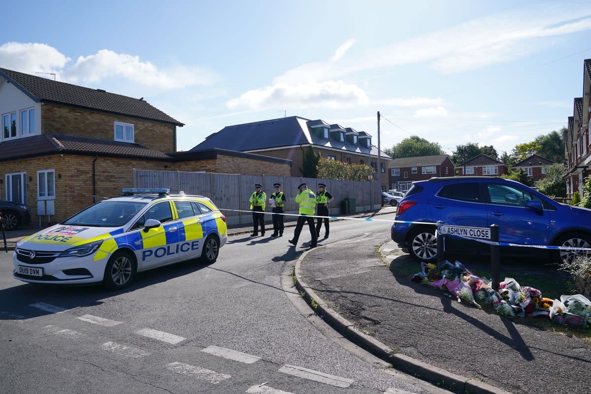 Police officers next to floral tributes at the scene in Ashlyn Close, Bushey (Jonathan Brady/PA Wire)
