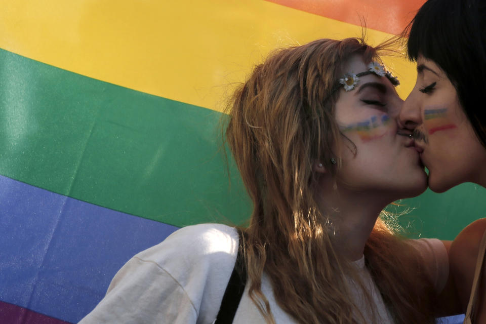 FILE - Two women kiss in front of a rainbow flag, the symbol of the gay rights movement, during the Gay Pride parade in central Athens, Saturday, June 14, 2014. Greece's center-right government will soon submit a draft law allowing same-sex civil marriages, despite reservations from its own lawmakers and the country's powerful church, Prime Minister Kyriakos Mitsotakis said Wednesday, Jan. 10, 2024. (AP Photo/Petros Giannakouris, File)