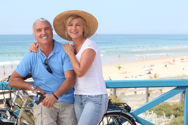 Mature couple with bikes by the beach