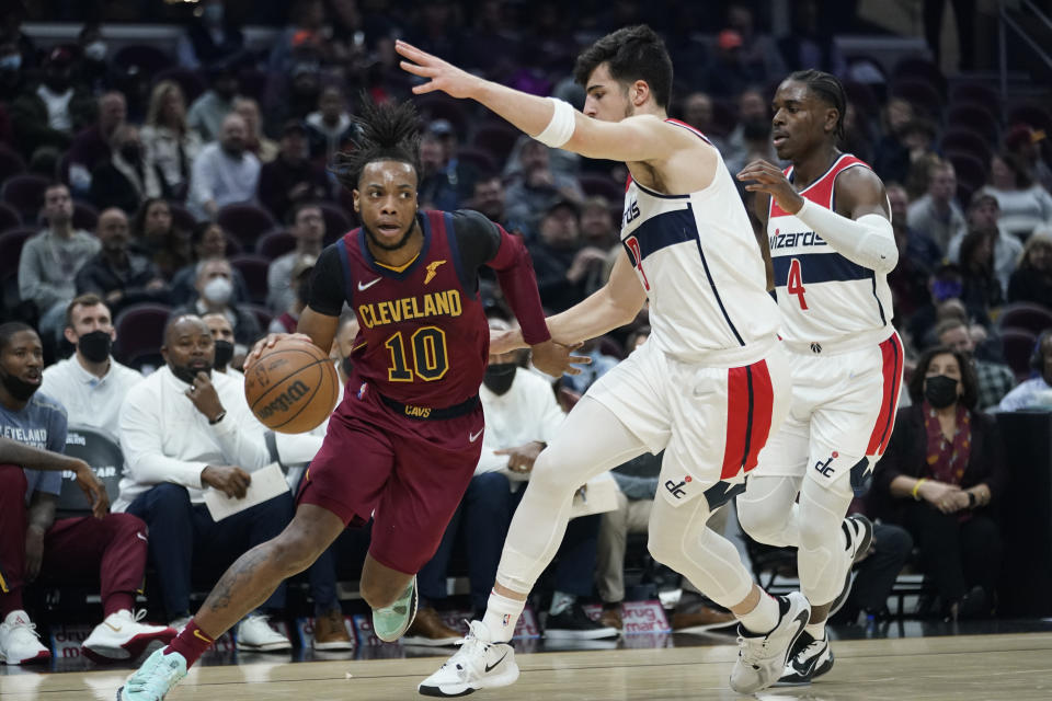 Cleveland Cavaliers' Darius Garland (10) drives against Washington Wizards' Deni Avdija (9) and Aaron Holiday (4) in the first half of an NBA basketball game, Wednesday, Nov. 10, 2021, in Cleveland. (AP Photo/Tony Dejak)