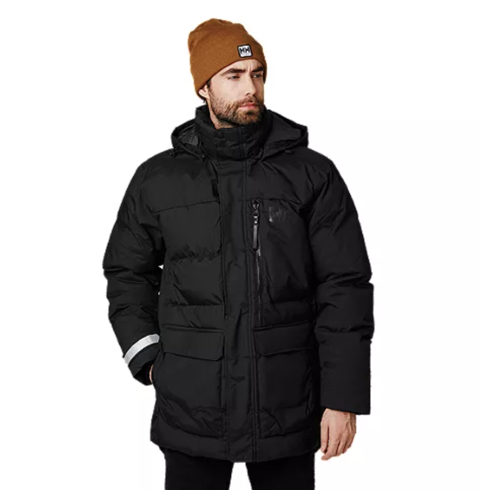 male model wearing black Helly Hansen Men's Tromsoe Insulated Jacket and brown hat (Photo via Sport Chek)