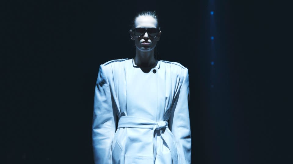 Bold, extra-wide shoulders on long coats gave models exaggerated silhouettes on the runway as they navigated the dark, cavernous Park Avenue Armory, illuminated by beams of light. - Khaite