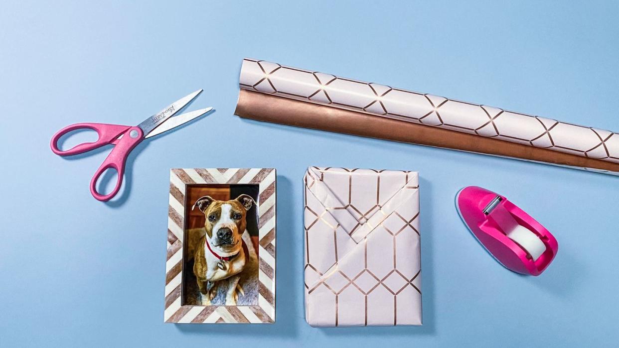 scissors, gift wrap, picture frame with dog photo in it, tape dispenser