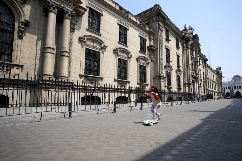 A youth plays in front of the government palace in Lima, Peru, Friday, Dec. 9, 2022. Peru's Congress voted to remove President Pedro Castillo from office Wednesday and replace him with the vice president, Boluarte, shortly after Castillo tried to dissolve the legislature ahead of a scheduled vote to remove him. (AP Photo/Fernando Vergara)