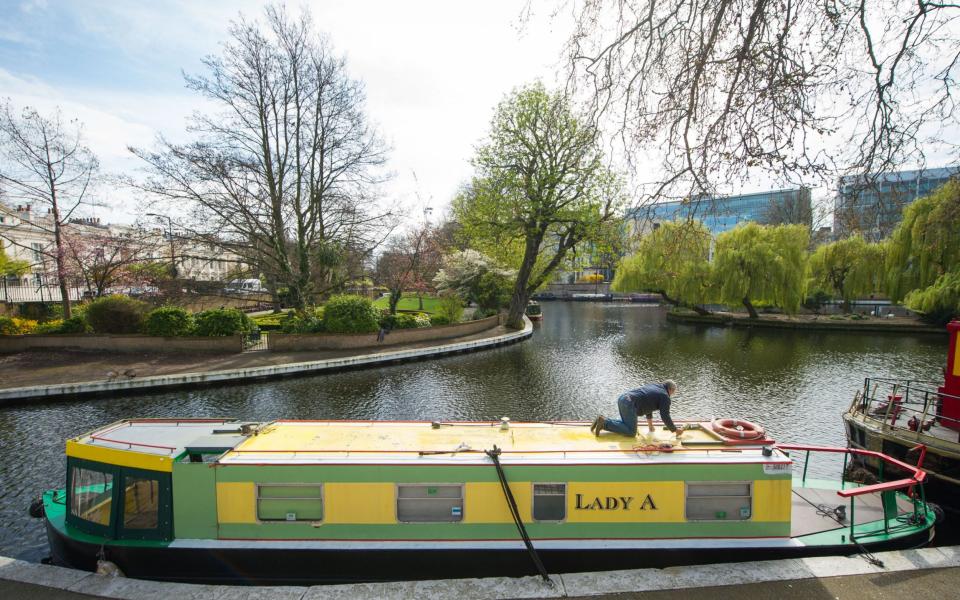 A man works on a narrowboat in Little Venice, London - Credit: Dominic Lipinski/PA