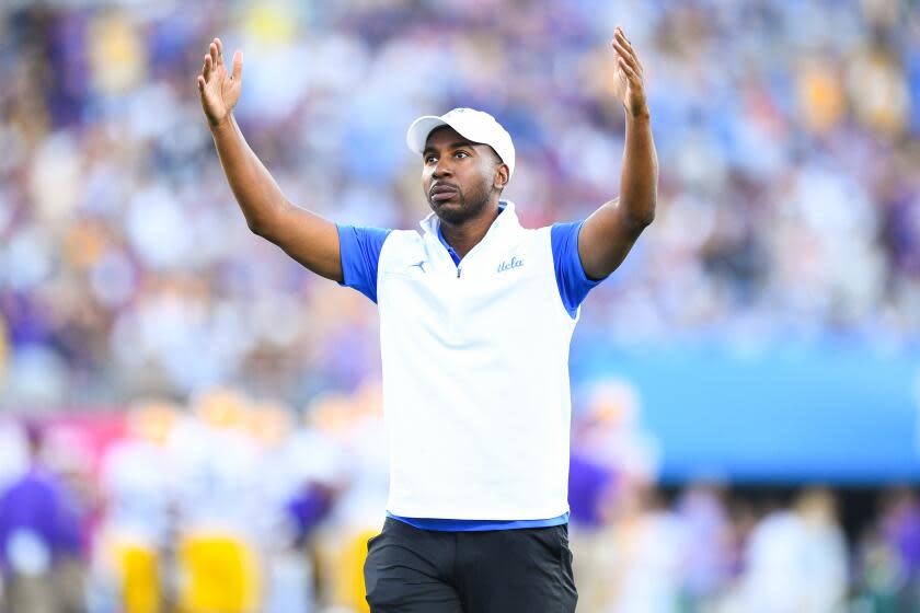 UCLA athletic director Martin Jarmond raises his arms and tries to pump up the crowd during a 2021 football game