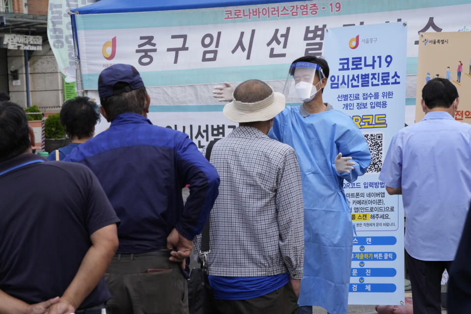 A medical worker guides people as they wait to get coronavirus testing at a makeshift testing site in Seoul, South Korea, Saturday, Sept. 25, 2021. (AP Photo/Ahn Young-joon)