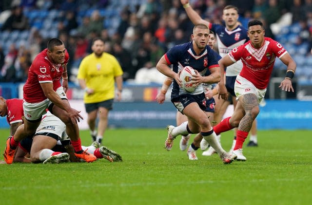 England’s Mikey Lewis, centre, runs with the ball against Tonga