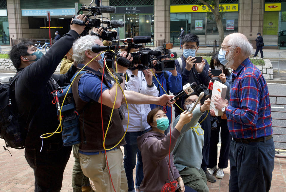 John Clancey, right, an American lawyer who became the first foreigner arrested under Hong Kong's national security law, displays a book before appearing at a police station in Hong Kong Sunday, Feb. 28, 2021. Clancey appeared at a police station Sunday, following a surprise request from police Friday. (AP Photo/Vincent Yu)