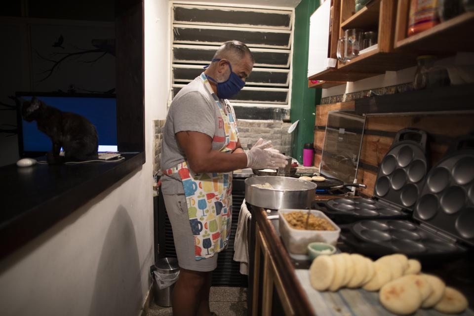 Andrés Burgos, un publicista de 55 años, hace arepas o empanadas de harina de maíz que distribuirá a los necesitados, en su casa de Caracas, Venezuela, el miércoles 21 de octubre de 2020. (AP Foto/Ariana Cubillos)