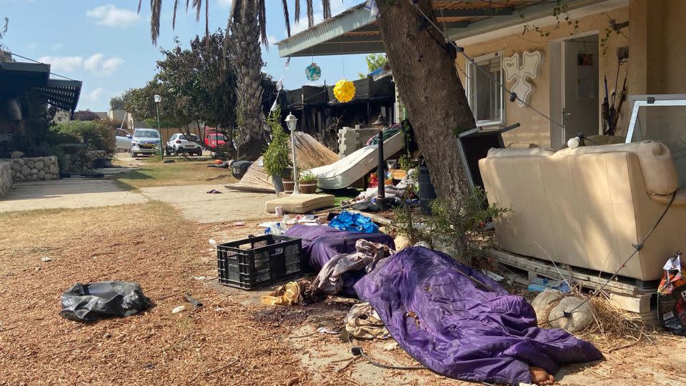 A covered body is seen lying on the ground in Kfar Aza.  - Muhammad Darwish/CNN