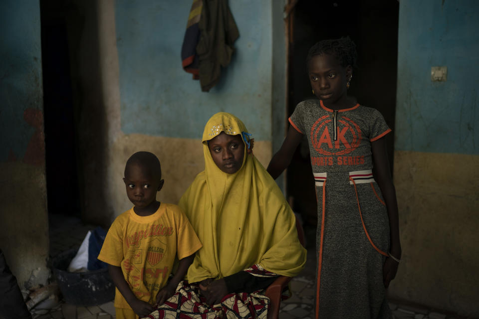 In this Nov. 24, 2018 photo, Mariama Konte, 20, sits with her daughter, Maimouna, 7, and her son, Ibrahima, 4, inside their home in a village near Goudiry, Senegal. Konte, who married Abdrahamane when she was 12 and he was 21, is living the consequences of the family's decision in November to mourn him after nearly four years of waiting. Friends and neighbors told them they would feel better if they went ahead with the ceremony, as five other families from the same shipwreck already had. (AP Photo/Felipe Dana)