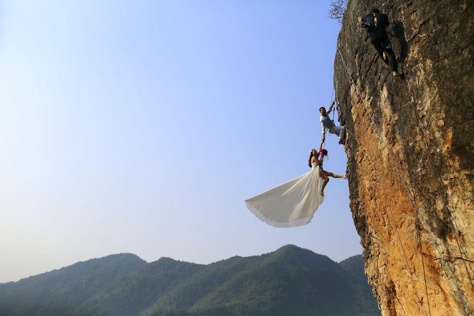 RNPS - REUTERS NEWS PICTURE SERVICE - PICTURES OF THE YEAR 2014 - ODDLY Zheng Feng, an amateur climber takes wedding pictures with his bride on a cliff in Jinhua, Zhejiang province, in this October 26, 2014 file photo. REUTERS/China Daily/Files (CHINA - Tags: SOCIETY TPX IMAGES OF THE DAY) CHINA OUT. NO COMMERCIAL OR EDITORIAL SALES IN CHINA