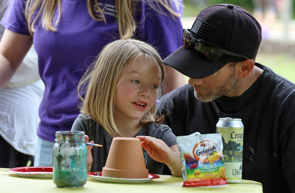 Five-year-old Isabella Hullett paints a flower pot with her dad, Jason Finny, during the Goat Island Games held Saturday, May 7, 2022, in Cramerton.