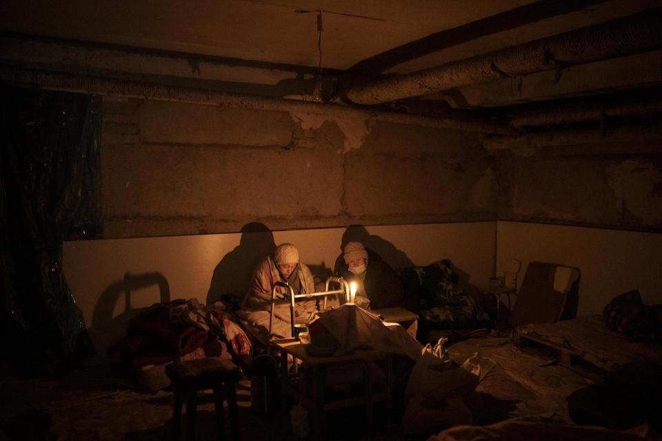 Zwei ältere Frauen verstecken sich bei Kerzenlicht in einem als Luftschutzbunker genutzten Keller in Irpin,  13. März 2022