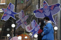 Residents wearing masks to protect from the coronavirus walks past decorations at a mall in Beijing, China, Friday, Jan. 21, 2022. The sweeping "zero-tolerance" policies that China has employed to protect its people and economy from COVID-19 may, paradoxically, make it harder for the country to exit the pandemic. (AP Photo/Ng Han Guan)