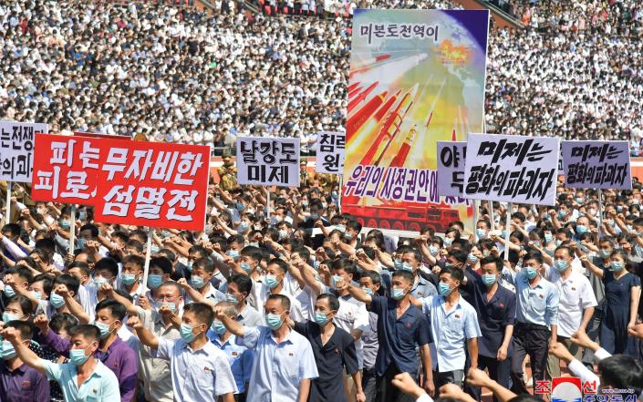 North Koreans hold anti-US propoganda placards at the rally in Pyongyang