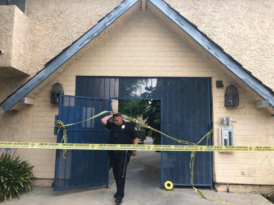 A Los Angeles police officer walks out of an apartment where a shooting occurred in Canoga Park on Thursday.  Police say a gunman shot five people, killing three, in two attacks in Los Angeles before he tried to rob someone outside a bank.