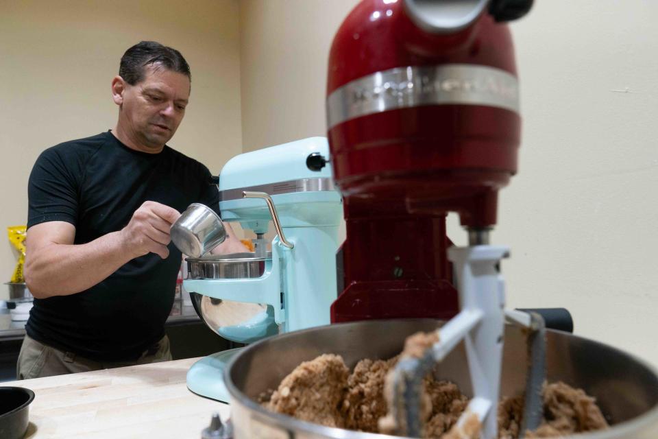John Husman, employee at The Forgotten Grain Bakery & Bistro, pours a measured amount of vegan chocolate chips into a stand mixer for cookies Thursday morning. Husman is also in charge of making the bagels.