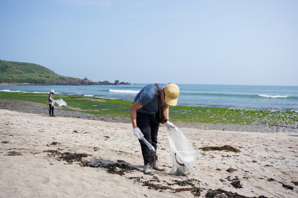 民眾在石門老梅綠石槽沙灘清理海岸垃圾。   圖：新北市環保局提供