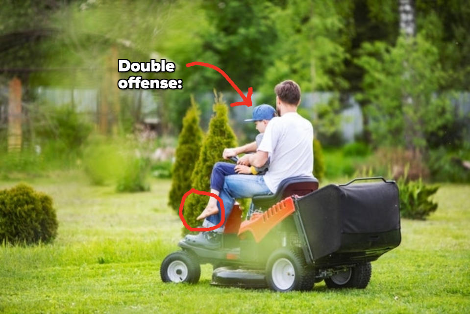 A man and child ride together on a lawnmower through a lush garden. The child wears a baseball cap and sits on the man's lap