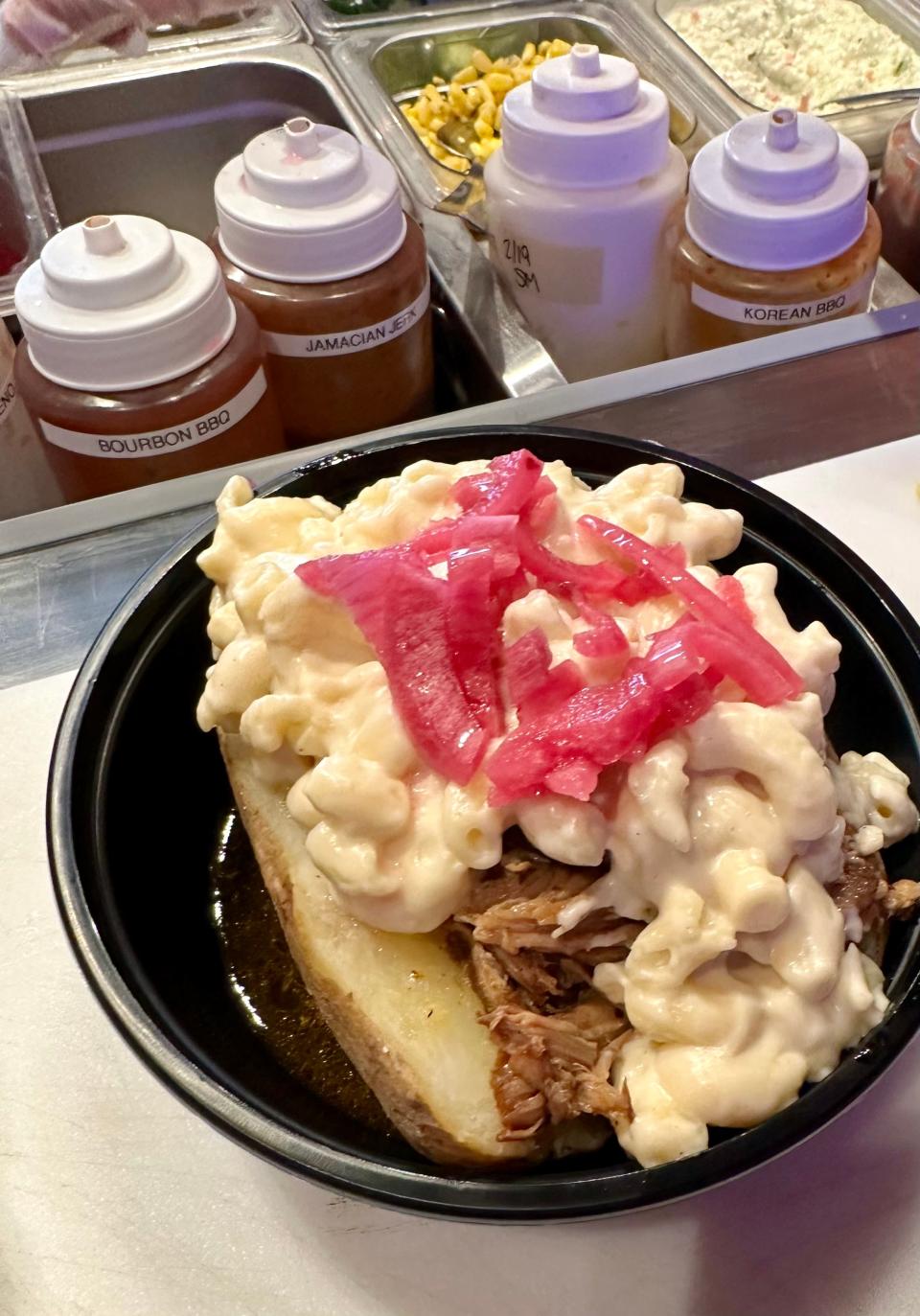 The large barbecue fusion bowl features a baked potato base, tender brisket, and pickled red onions, all ready to be sauced at The Blazing Pig.