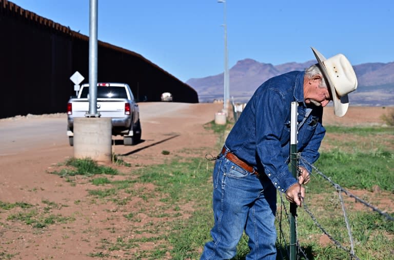 L'éleveur John Ladd ajuste la clôture endommagée délimitant ses terres, le long du mur à la frontière entre les Etats-Unis et le Mexique, le 17 avril 2024 près de Palominas, en Arizona (Frederic J. BROWN)