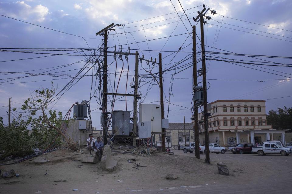 In this July 29, 2019 photo, Ethiopian Oromo migrants sit under electric cables in Al Hosoun area, where they gather to find work, in Marib, Yemen. In the evenings, thousands of migrants mill around the streets of Marib, one of the main city stopovers on the migrants' route through Yemen. In the mornings, they search for day jobs. They could earn about a dollar a day working on nearby farms. A more prized job is with the city garbage collectors, paying $4 a day. (AP Photo/Nariman El-Mofty)