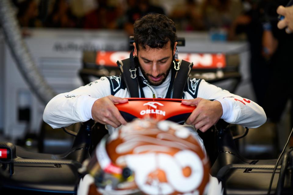 F1 driver Daniel Ricciardo climbs into his car.