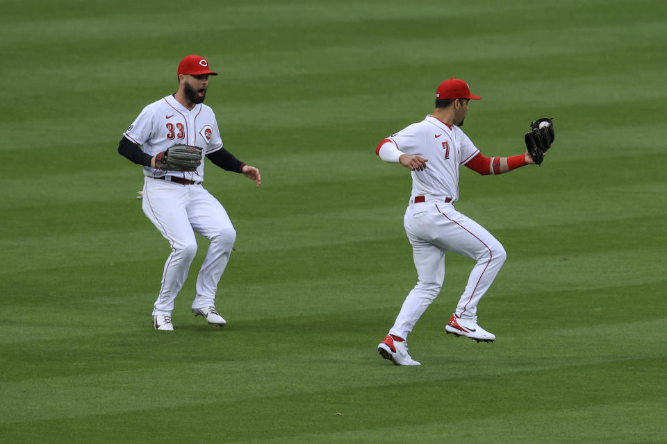 Cincinnati Reds' Jesse Winker, left, watches as Eugenio Suarez makes a catch for an out on a ball hit by Arizona Diamondbacks' Nick Ahmed during the third inning of a baseball game in Cincinnati, Tuesday, April 20, 2021. (AP Photo/Aaron Doster)