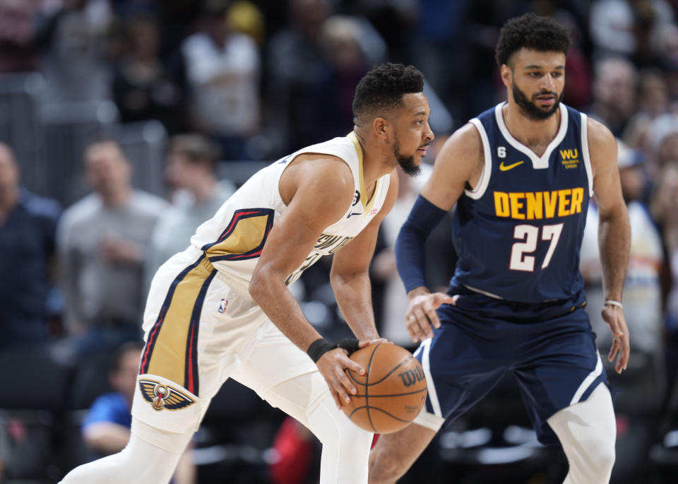 New Orleans Pelicans guard CJ McCollum, front, looks to pass the ball as Denver Nuggets guard Jamal Murray defends in the first half of an NBA basketball game Tuesday, Jan. 31, 2023, in Denver. (AP Photo/David Zalubowski)