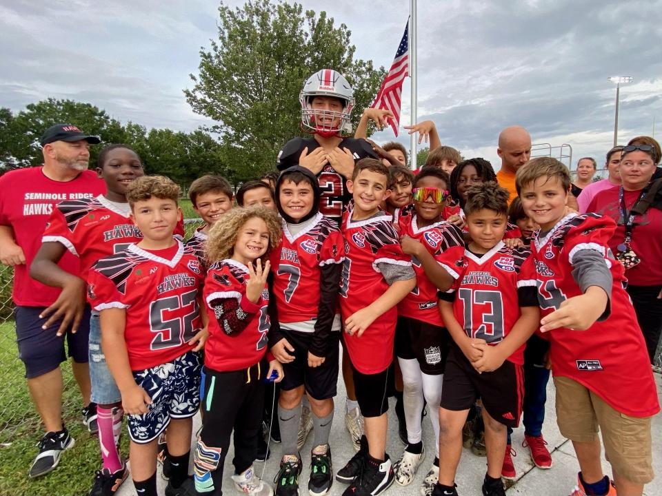 Seminole Ridge running back Robbie Venero poses with football players from the Acreage League in Loxahatchee after winning The Post's Athlete of the Week during the 2023 high school football season.