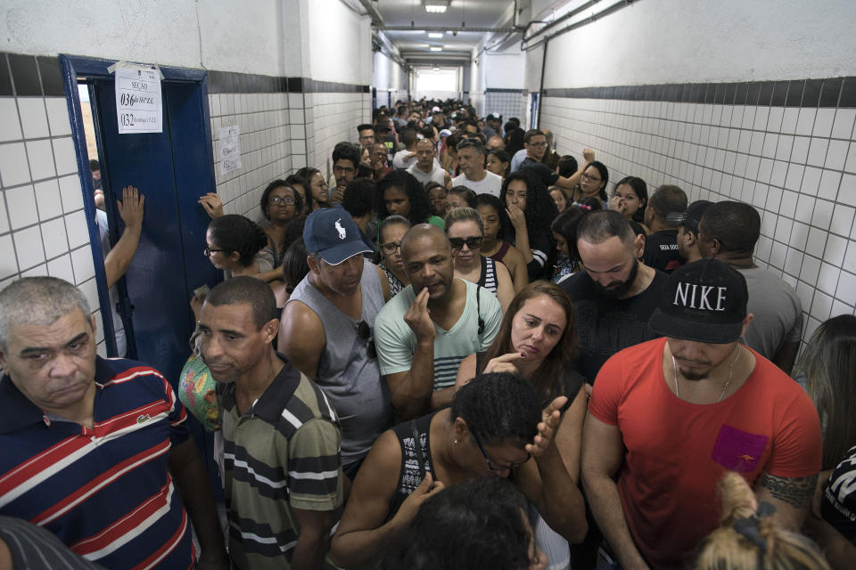 People wait in line to vote in the general election at a polling station in the Mare Complex slum in Rio de Janeiro, Brazil, Sunday, Oct. 7, 2018. Brazilians choose among 13 candidates for president Sunday in one of the most unpredictable and divisive elections in decades. If no one gets a majority in the first round, the top two candidates will compete in a runoff. (AP Photo/Leo Correa)