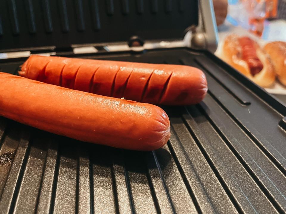 two hot dogs cooking on an indoor grill