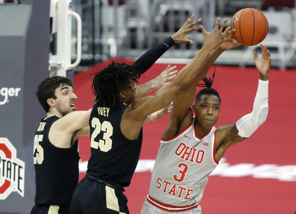 Ohio State guard Eugene Brown, right, passes against Purdue guard Ethan Morton, left, and guard Jaden Ivey during the first half of an NCAA college basketball game in Columbus, Ohio, Tuesday, Jan. 19, 2021. (AP Photo/Paul Vernon)