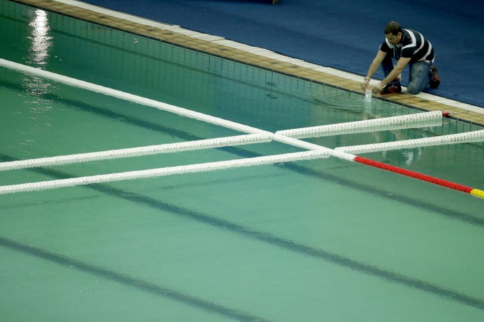 An inspector takes a sample from the water polo pool which turned green in color today in the Maria Lenk Aquatic Center at the 2016 Summer Olympics in Rio de Janeiro, Brazil, Wednesday, Aug. 10, 2016. (AP Photo/Matt Dunham)