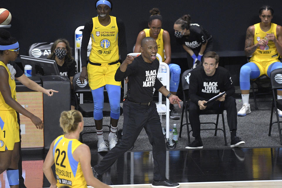 Chicago Sky players on the bench in yellow jerseys with coach James Wade pumping his fist in a "Black Lives Matter" T-shirt.