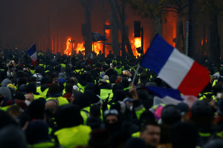 A French flag is held by protesters wearing yellow vests, a symbol of a drivers' protest against higher diesel taxes, who demonstrate near the Place de l'Etoile in Paris, France, December 1, 2018. REUTERS/Stephane Mahe