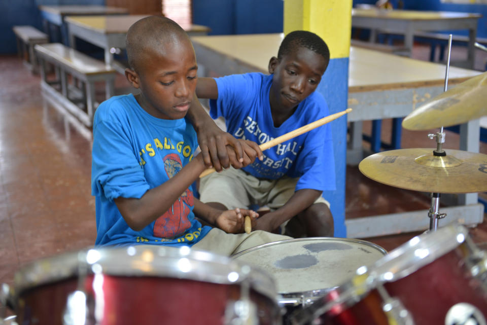 In this Feb. 17, 2014 photo, 14-year-old Brad Hylton helps classmate Omar Bird play a drum beat with the band at Alpha Boys’ School, a residential vocational school in Kingston, Jamaica. The school has been a cornerstone of Jamaica’s prolific musical culture for over a century, producing numerous musicians who have taken the homegrown musical genres of ska, rocksteady and reggae to the world. (AP Photo/David McFadden)