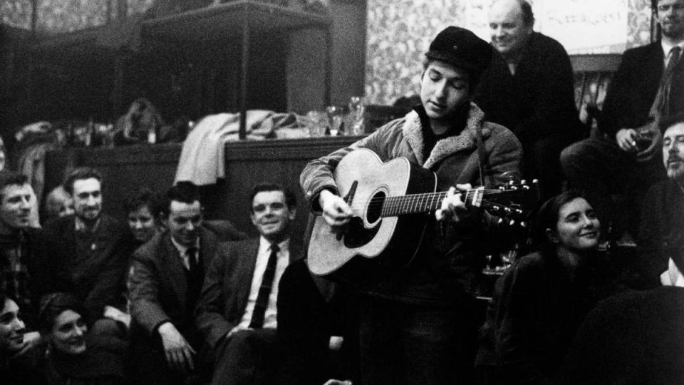 Man performing music; young bob Dylan