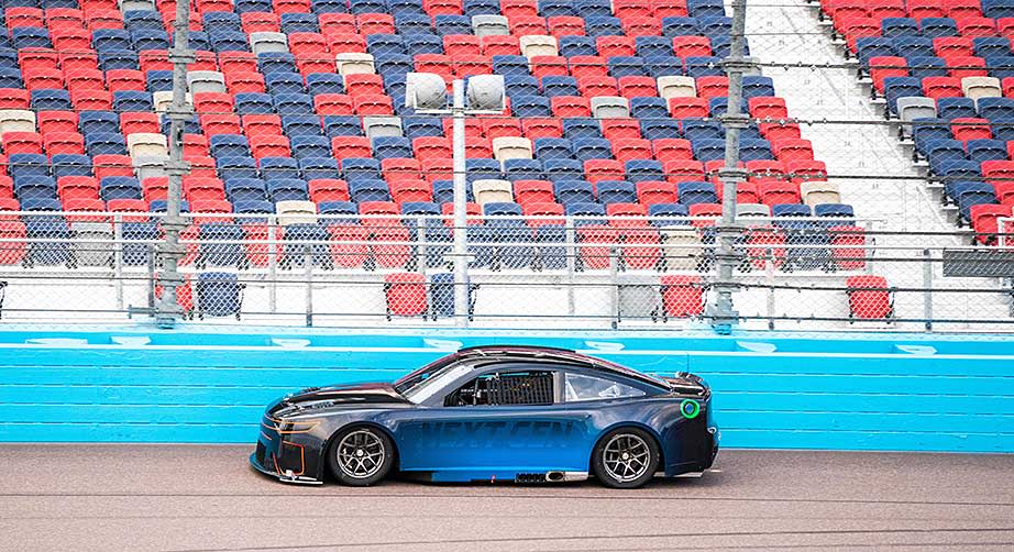 Joey Logano drives the Next Gen prototype, with smaller rear spoiler, near the outside retaining wall at ISM Raceway.